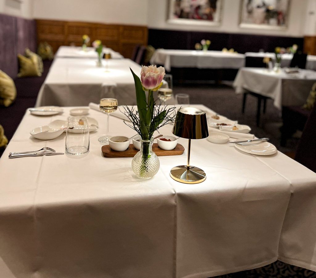 Schön eingedeckter Tisch mit weißer Tischdecke und Geschirr und Blumen.